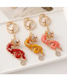 Detailed close-up of three colorful rhinestone zodiac dragon keychains on a white tray
