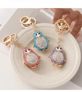 Vue détaillée de porte-clés manchots en strass rose, bleu et violet sur plat blanc