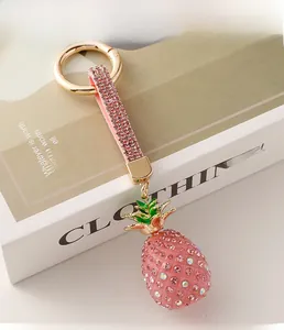 Close-up of pink rhinestone pineapple keychain with golden ring and sparkling strap