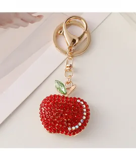 Close-up of a sparkling red rhinestone apple keychain with gold hardware and green leaf