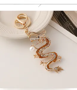 Détail d'un porte-clés dragon doré orné de strass et d'une perle sur assiette