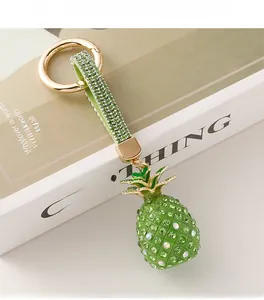 Close-up of a sparkling green pineapple keychain with rhinestones and a leather strap