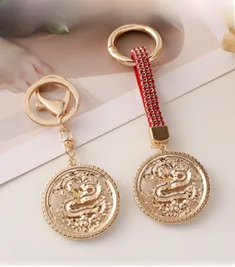 Detailed close-up of golden alloy dragon keychain with red crystal ribbon and hollow design