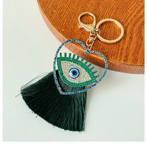 Détail de porte-clés en cœur avec l'œil porte-bonheur et gland en soie vert foncé