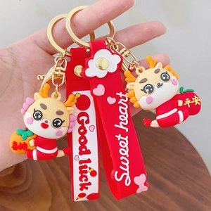 Cartoon Chinese dragon keychains with lucky charms and red straps on a wooden table