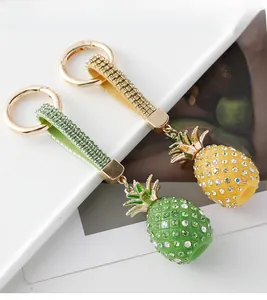 Close-up of rhinestone-studded pineapple keychains in yellow and green with leather straps