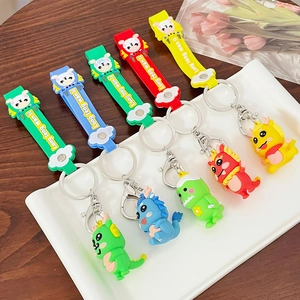 Set of 5 colorful cartoon dragon keychains with silicone straps on a white tray