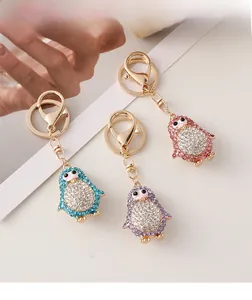 Vue détaillée de trois porte-clés pingouins en strass colorés en bleu, violet et rose