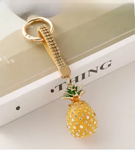 Detail of a sparkling pineapple keychain with yellow rhinestones and green leaf enamel