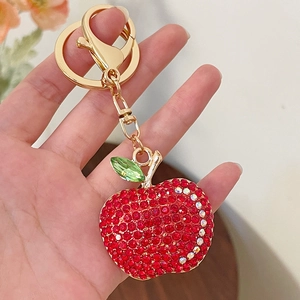 Sparkling red rhinestone apple keychain with gold metal clasp held in hand for scale