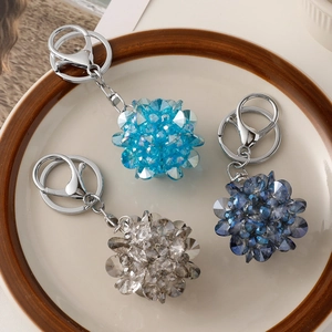 Trois porte-clés boule en cristal bleu et transparent sur une assiette en porcelaine