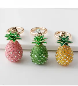 Detailed view of three sparkling rhinestone pineapple keychains in pink, green, and yellow