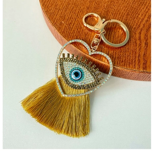 Gros plan d'un porte-clés œil protecteur en forme de cœur avec strass et pompon jaune