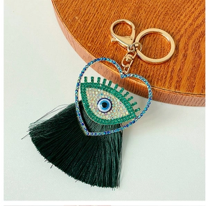 Détail du pendentif cœur mauvais œil en cristal étincelant avec un gland en soie vert foncé