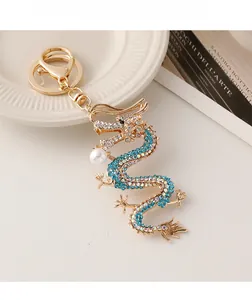 Détail du porte-clés dragon doré orné de strass bleus brillants et d'une perle blanche fine