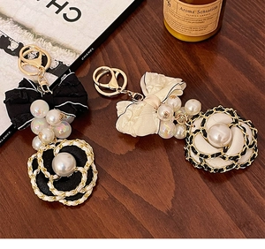 Close-up of handmade camellia flower keychain with silk bow and faux pearls decoration