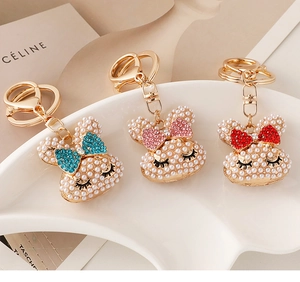 Close-up of pearl-studded rabbit keychains with colorful bowknots on a ceramic plate