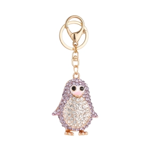Porte-clés pingouin étincelant avec cristaux violets et blancs sur une base en métal doré