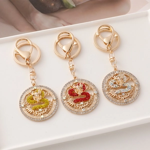 Three Chinese zodiac dragon keychains with colorful rhinestones on a white ceramic plate