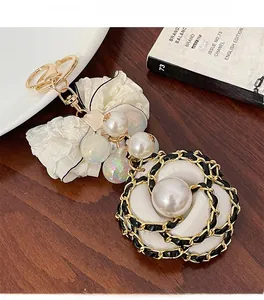 Detail of camellia floral charm with lace bow, pearls, and gold-tone chain on a keychain