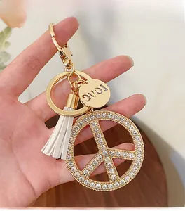 Detailed macro view of crystal peace sign keychain with white tassel and love charm