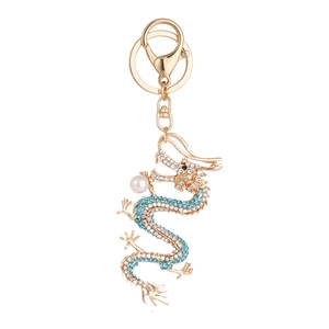Porte-clés dragon doré avec strass colorés et perle blanche sur un fond blanc pur