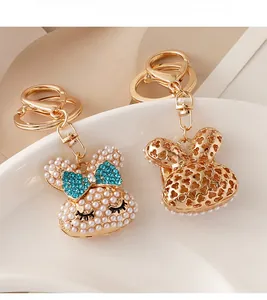 Close-up of pearl-studded rabbit and hollow heart metal bunny keychains on a white ceramic plate