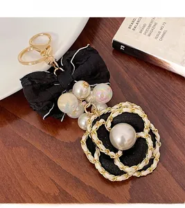 Detail of camellia bow keychain with faux pearls and gold chain link on wooden desk