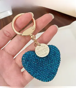 Detail of blue rhinestone heart keychain with gold ring and engraved round metal tag