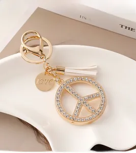 Detail of peace sign keychain with white tassels and sparkling crystal embellishments