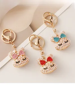 Detail of cute pearl rabbit keychains with pink red and blue rhinestone bows