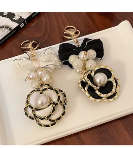 Detail of camellia flower and pearl bow keychains in black and white fabric
