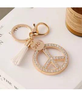 Detail of peace sign keychain with white tassels and sparkling rhinestones on golden metal