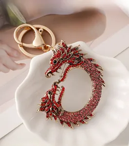 Détail d'un porte-clés dragon doré avec strass rouges et roses sur une assiette coquillage