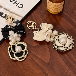 Elegant camellia bow keychain set with pearls and woven chain in black and white colors