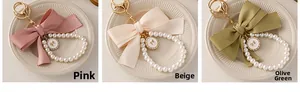 Detailed close-up of ribbon bow pearl keychains in pink, beige, and grass green colors