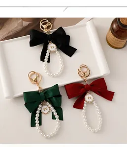 Close-up of elegant bow pearl keychains in black, dark green, and burgundy satin fabric