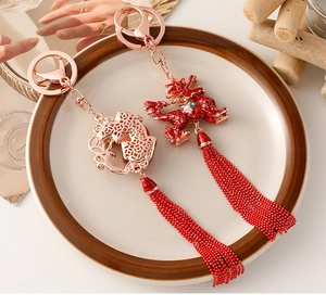 Close-up of red dragon charm and rose gold coin pendant with long beaded tassels