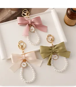 Detailed view of pink and green satin ribbon bow keychains with white pearl beads