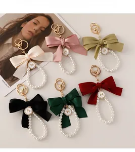 Flat lay of satin bow pearl keychains in cream, pink, olive, black and burgundy colors