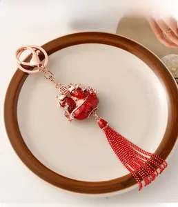 Detailed macro view of a red enamel koi fish pendant with rose gold metal and long tassel