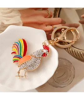 Close-up of colorful enamel rooster keychain with white crystal rhinestones in a dish