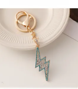 Detail of hip hop lightning keychain with blue and white crystals on a gold plated finish