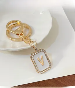 Dettaglio di un portachiavi dorato con ciondolo rettangolare con diamanti e la lettera V