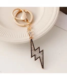 Close-up of golden lightning bolt keychain with black and white rhinestones on white plate