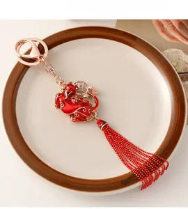 Detailed close-up of a festive red Pi Xiu keychain with rose gold accents and red silk tassels