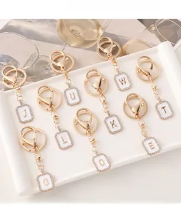 Portachiavi chic placcati in oro con lettere e strass su un piatto di ceramica bianco