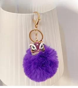Gros plan sur un porte-clés lion chinois violet avec pompon en fourrure et clip doré