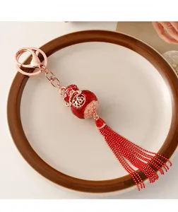 Detail view of a Chinese red gourd tassel keychain with gold Fu character and rose gold clasp