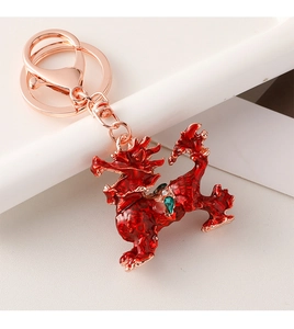 Close-up of red enamel Kirin keychain with rose gold metal scales and gemstones